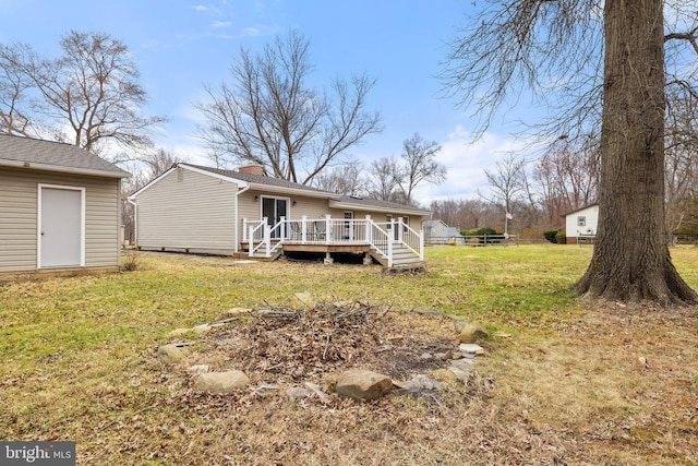 back of property with a yard, an outdoor structure, a deck, and fence