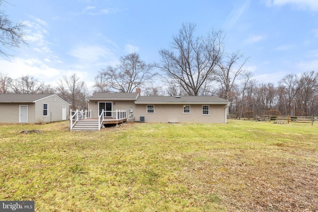 back of house featuring fence, stucco siding, a chimney, a deck, and a lawn