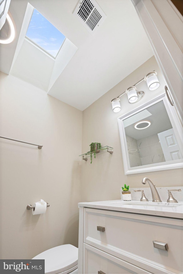 half bath featuring vanity, a skylight, toilet, and visible vents