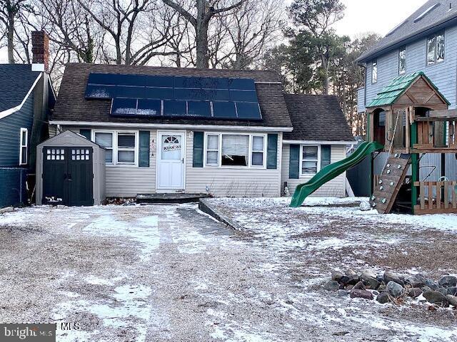 view of front of property featuring solar panels, a playground, and a shed