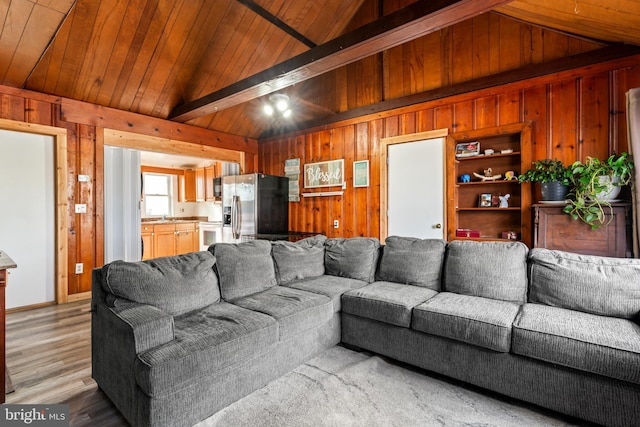 living room featuring vaulted ceiling, wooden ceiling, wood walls, and built in shelves