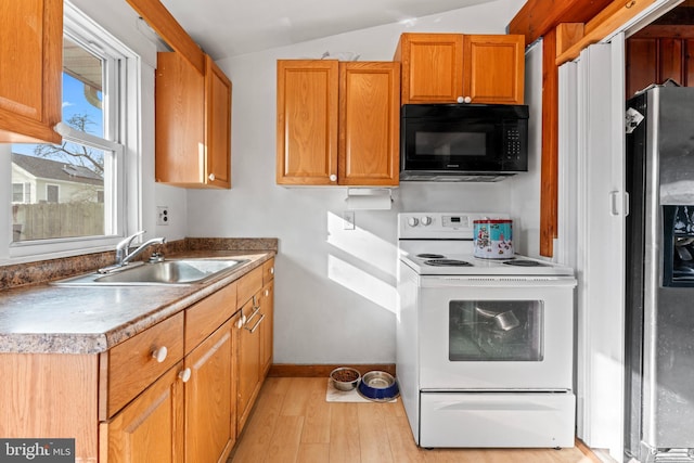 kitchen featuring electric range, vaulted ceiling, light hardwood / wood-style floors, stainless steel fridge, and sink