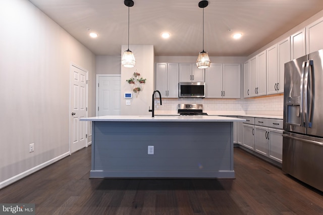 kitchen featuring stainless steel appliances, sink, a kitchen island with sink, and decorative light fixtures