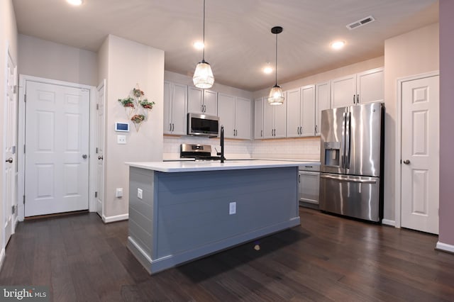 kitchen featuring backsplash, hanging light fixtures, dark wood-type flooring, an island with sink, and stainless steel appliances