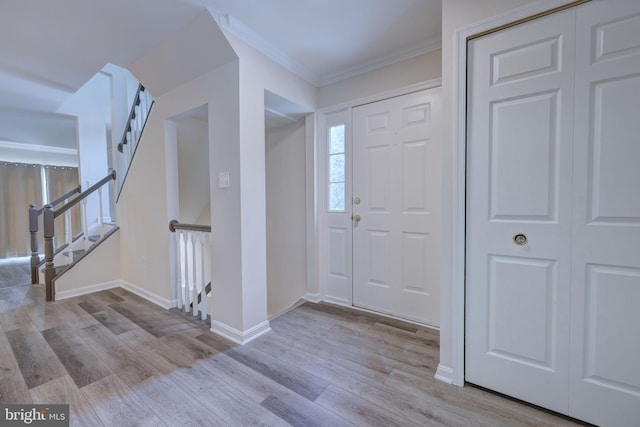 foyer with crown molding and light hardwood / wood-style floors