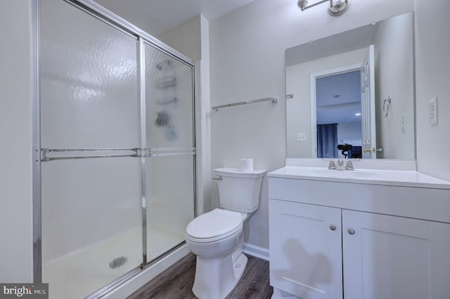 bathroom with toilet, hardwood / wood-style floors, walk in shower, and vanity