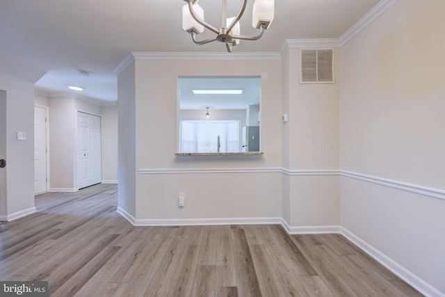 unfurnished dining area featuring light hardwood / wood-style floors, ornamental molding, and an inviting chandelier