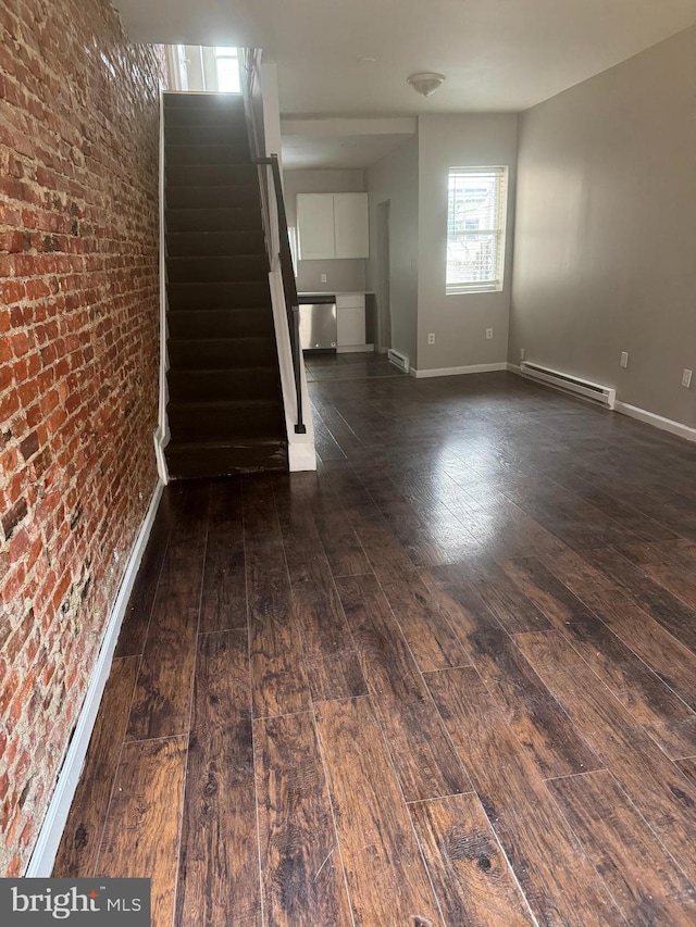 unfurnished room with baseboard heating, dark wood-type flooring, and brick wall