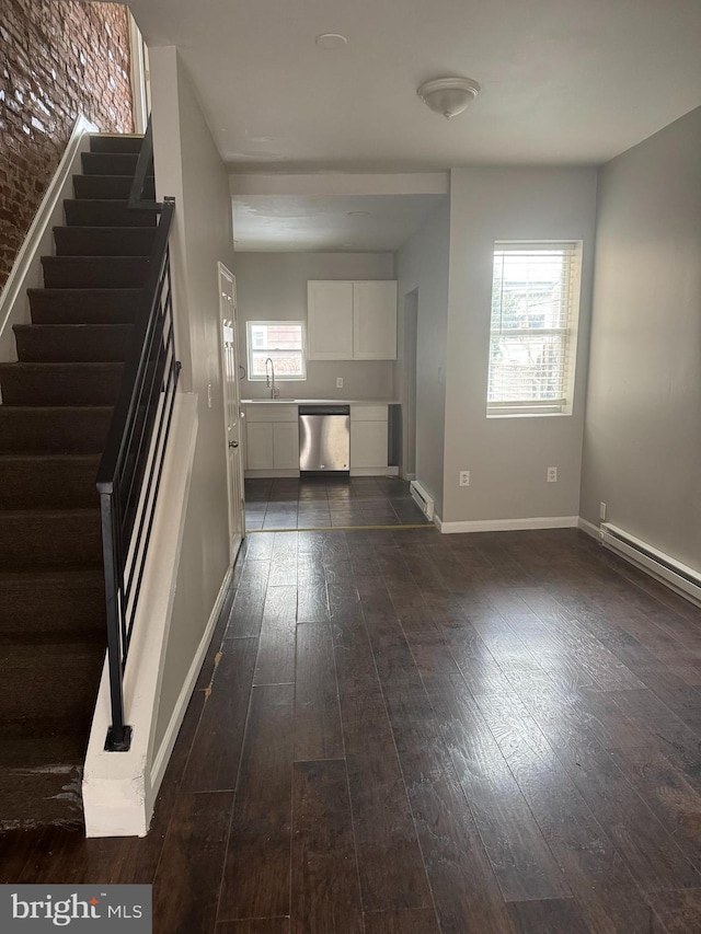 unfurnished living room with sink, a baseboard radiator, dark wood-type flooring, and plenty of natural light