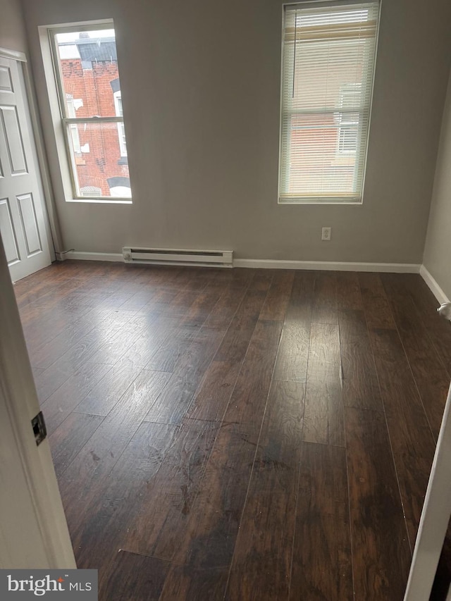 empty room featuring baseboard heating and dark hardwood / wood-style flooring