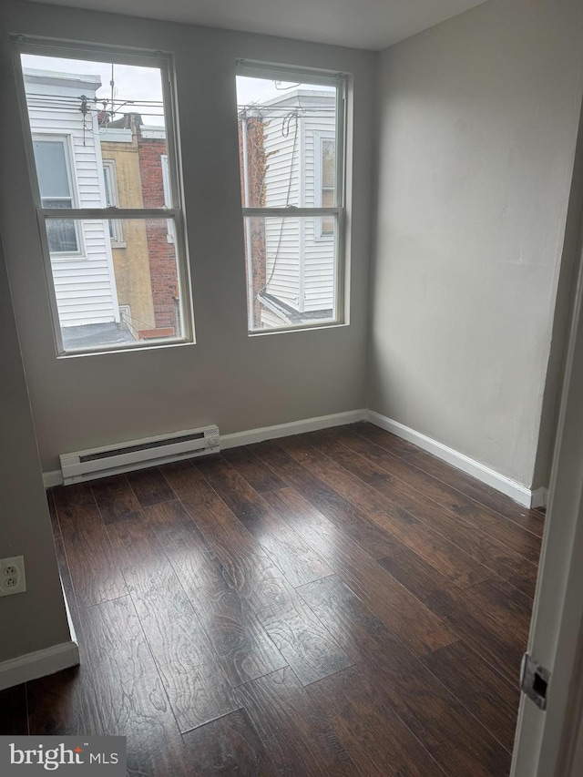 spare room featuring an inviting chandelier, dark hardwood / wood-style flooring, and a baseboard radiator