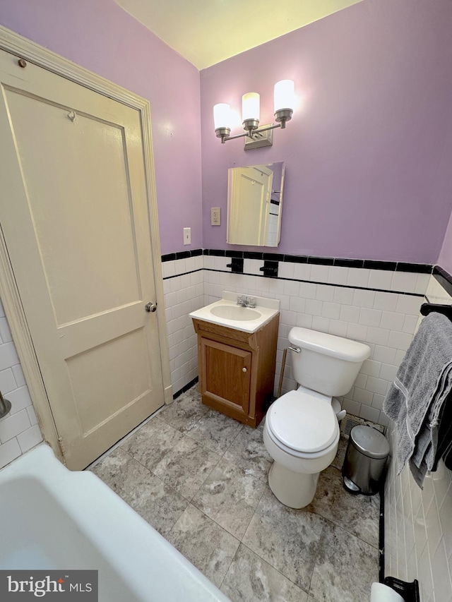 bathroom with vanity, tile walls, and toilet