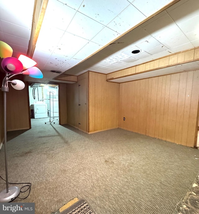 basement with washer / clothes dryer, wood walls, and carpet