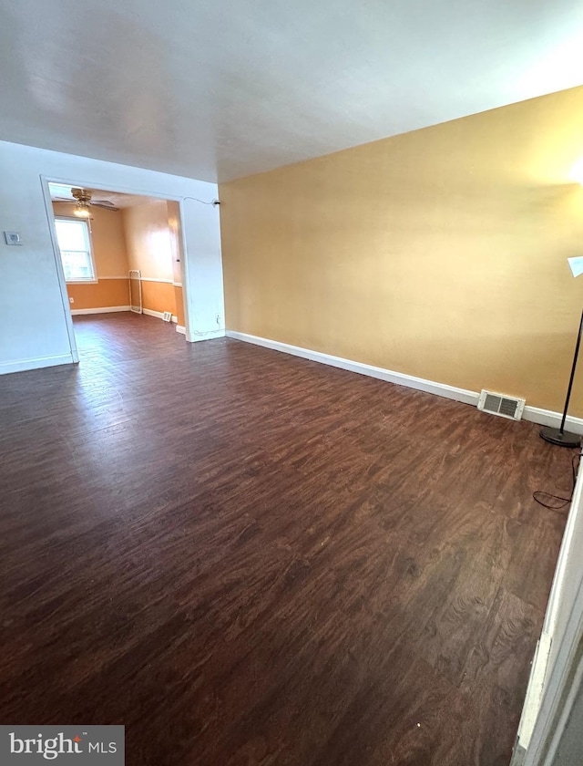 empty room with ceiling fan and dark wood-type flooring