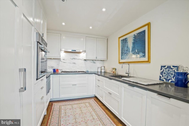 kitchen featuring light hardwood / wood-style flooring, stainless steel appliances, tasteful backsplash, white cabinetry, and sink