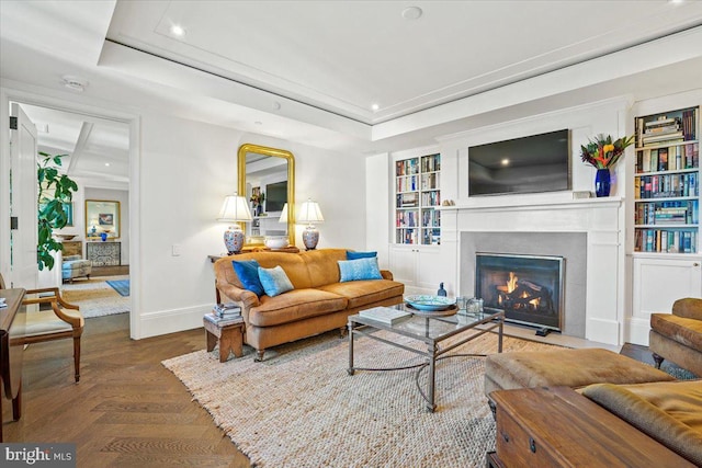 living room with parquet floors, built in shelves, and a tray ceiling