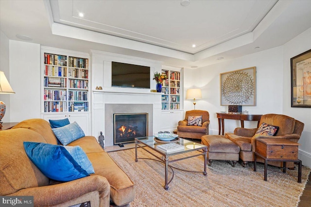 living room featuring a raised ceiling and built in features