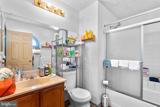 full bathroom with enclosed tub / shower combo, vanity, toilet, and a textured ceiling