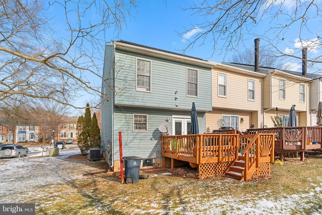 snow covered property with central air condition unit and a deck