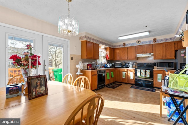 kitchen featuring pendant lighting, a textured ceiling, light hardwood / wood-style floors, and black appliances