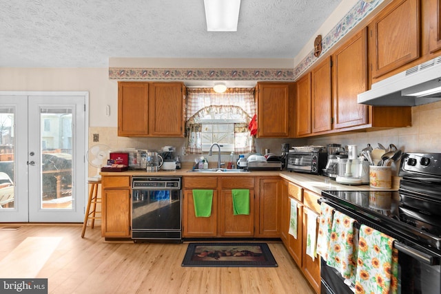 kitchen featuring sink, light hardwood / wood-style flooring, black appliances, a textured ceiling, and french doors