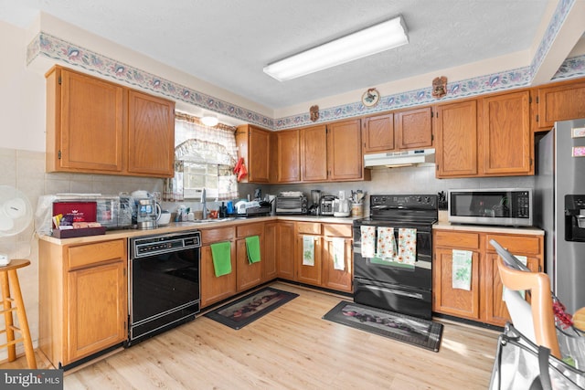 kitchen featuring backsplash, light hardwood / wood-style floors, a textured ceiling, and black appliances