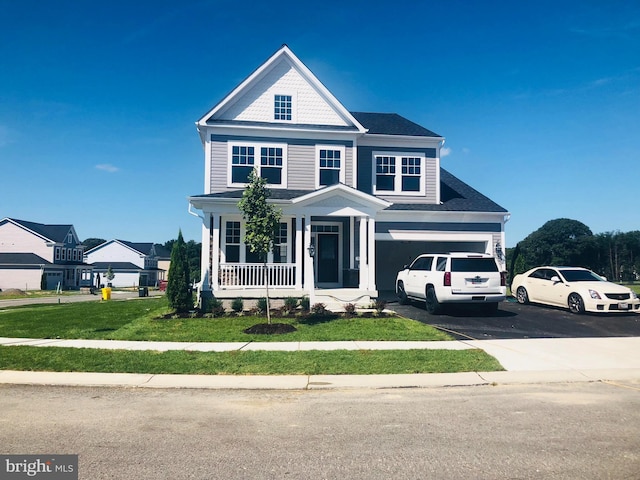 view of front of home with a front yard, covered porch, and a garage