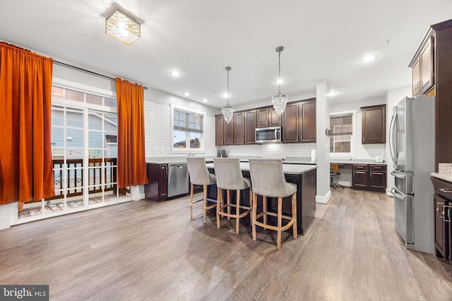 kitchen featuring stainless steel appliances, hardwood / wood-style flooring, dark brown cabinetry, and decorative light fixtures