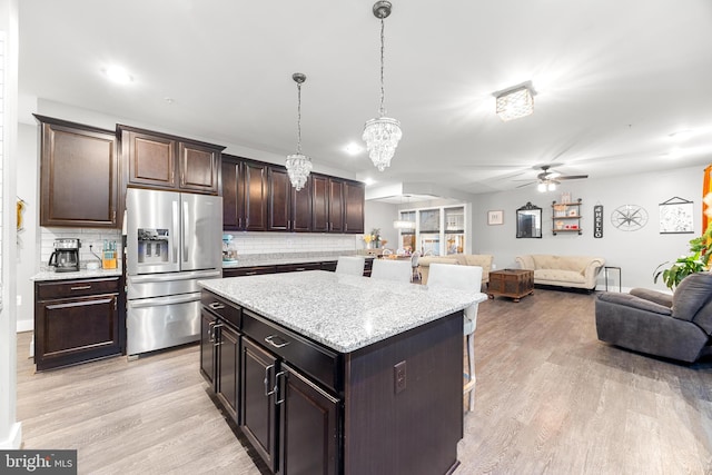 kitchen with decorative light fixtures, stainless steel fridge with ice dispenser, dark brown cabinets, and a kitchen island