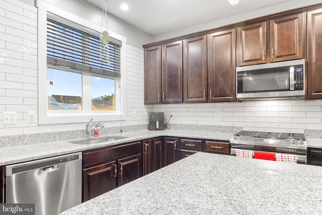 kitchen with light stone counters, sink, backsplash, and appliances with stainless steel finishes