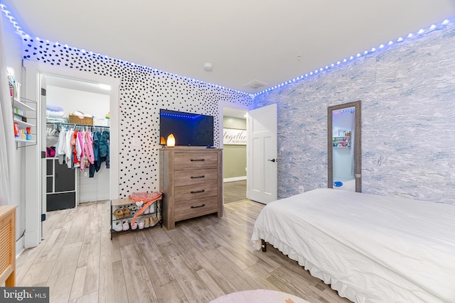 bedroom featuring a spacious closet, a closet, and light wood-type flooring