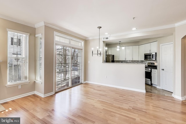 kitchen featuring stainless steel appliances, white cabinetry, decorative light fixtures, and a wealth of natural light