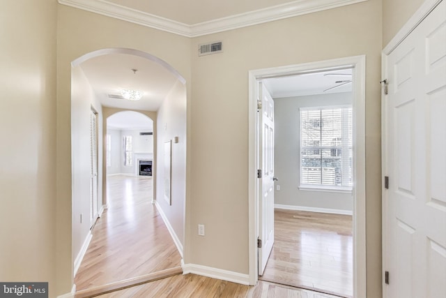 hall with light wood-type flooring and ornamental molding