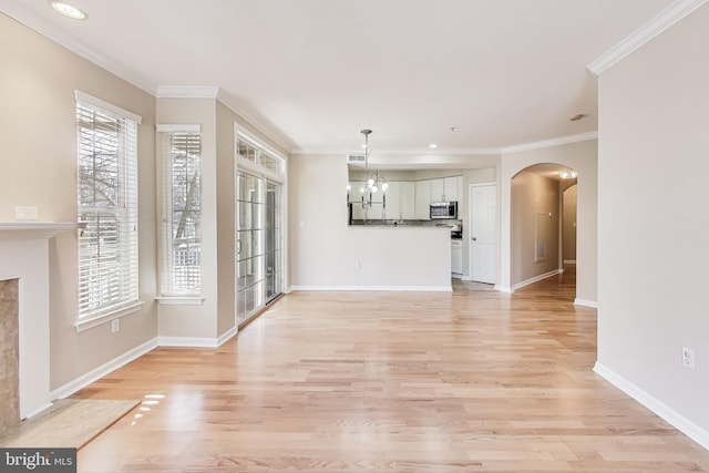 unfurnished living room featuring an inviting chandelier, light wood-type flooring, and crown molding