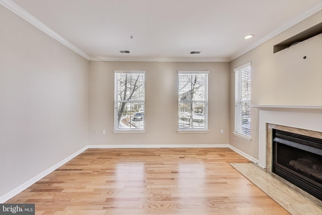 unfurnished living room featuring crown molding, light hardwood / wood-style flooring, a high end fireplace, and plenty of natural light