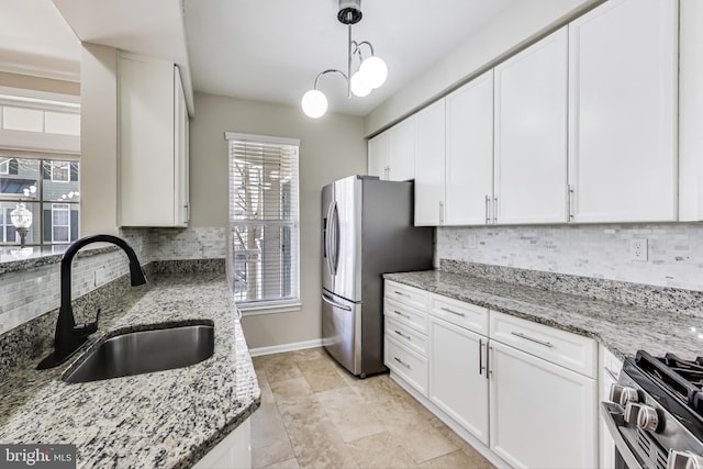 kitchen with sink, white cabinets, light stone counters, and appliances with stainless steel finishes