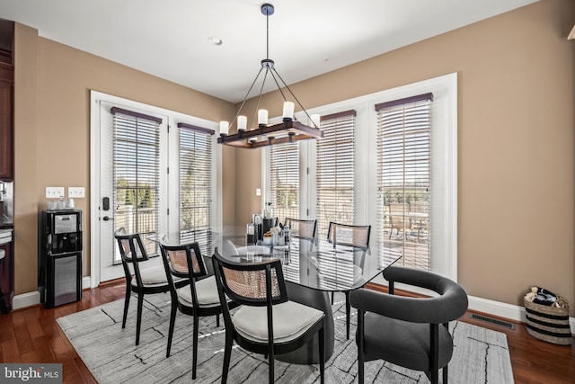 dining space featuring visible vents, baseboards, an inviting chandelier, and dark wood finished floors