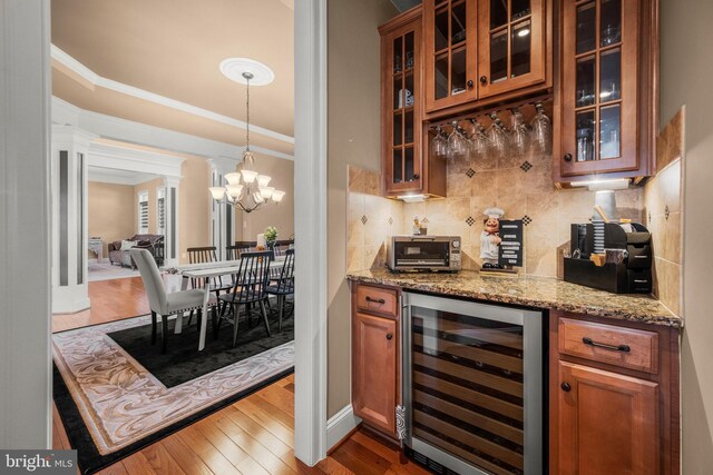 bar featuring ornamental molding, wine cooler, decorative backsplash, a dry bar, and dark wood-style flooring