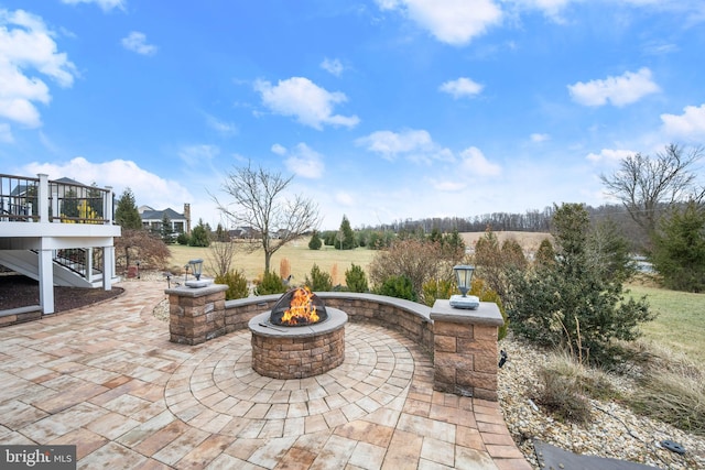 view of patio / terrace featuring a wooden deck, stairway, and an outdoor fire pit