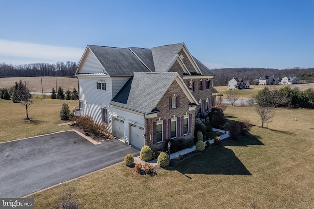 view of home's exterior featuring aphalt driveway, a yard, roof with shingles, a garage, and brick siding