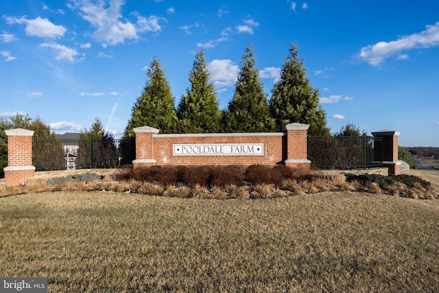 community / neighborhood sign featuring a yard and fence