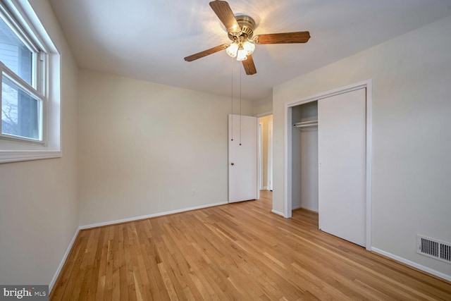 unfurnished bedroom featuring ceiling fan, multiple windows, light hardwood / wood-style flooring, and a closet