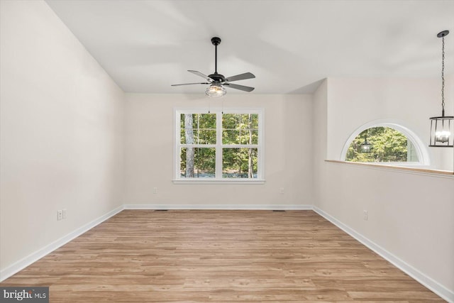 unfurnished room featuring light hardwood / wood-style flooring, a healthy amount of sunlight, and ceiling fan with notable chandelier