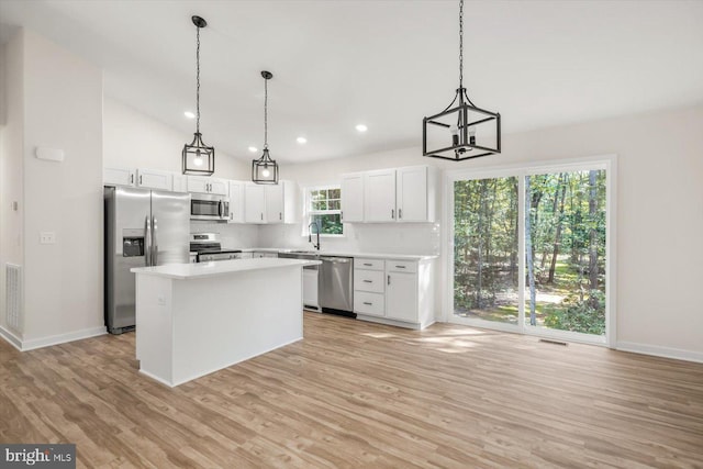 kitchen with appliances with stainless steel finishes, a center island, white cabinetry, and pendant lighting