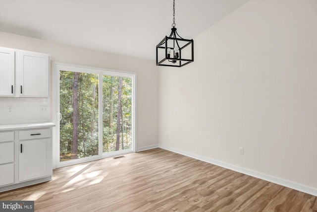 unfurnished dining area with light wood-type flooring and an inviting chandelier