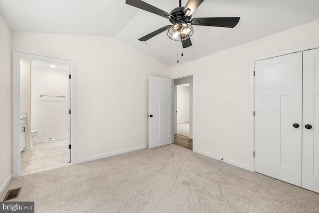 unfurnished bedroom with ceiling fan, lofted ceiling, light carpet, and a closet