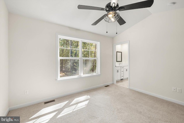 unfurnished bedroom with ceiling fan, light colored carpet, lofted ceiling, and ensuite bathroom