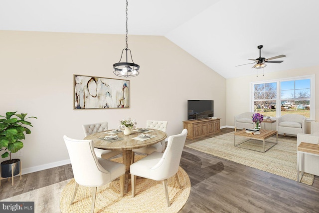 dining space with ceiling fan with notable chandelier, dark hardwood / wood-style floors, and vaulted ceiling