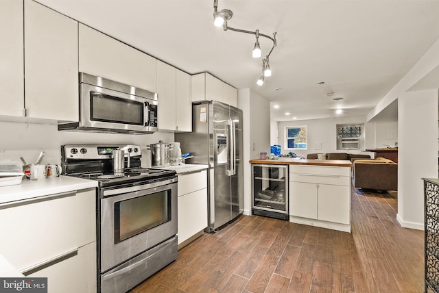 kitchen with white cabinets, appliances with stainless steel finishes, kitchen peninsula, and wine cooler