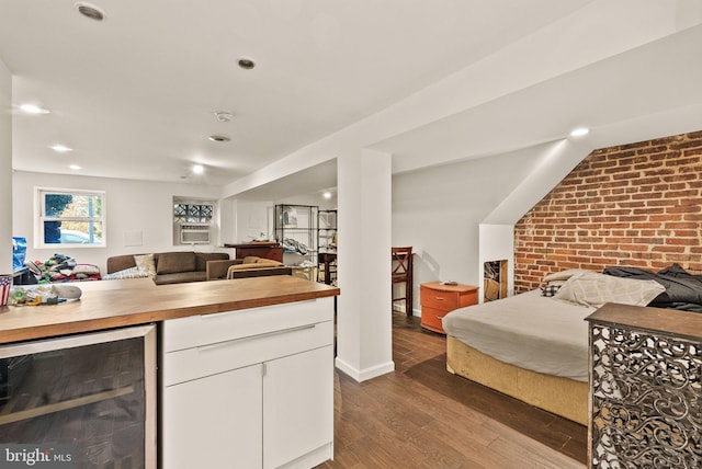 kitchen with wine cooler, brick wall, dark wood-type flooring, butcher block countertops, and white cabinetry